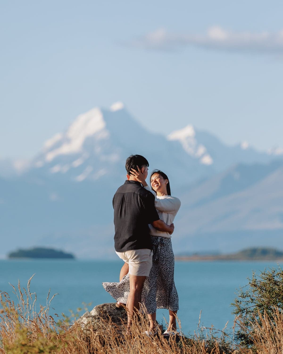 Couple embracing with Mt Cook backdrop during proposal photography at Lake Pukaki, New Zealand, in warm afternoon light.