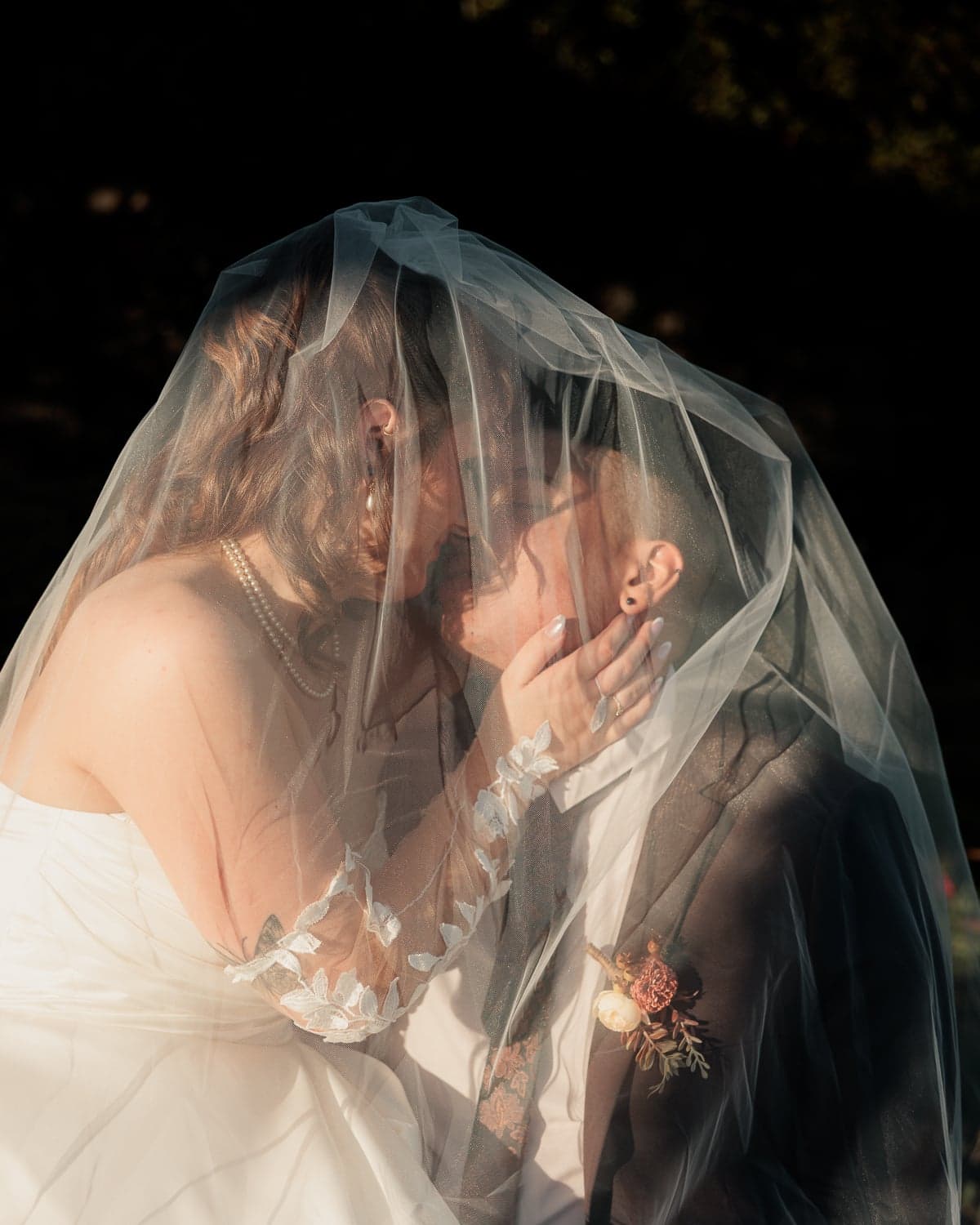 Bride and groom nearly kissing under a sheer veil in warm light, intimate wedding photography in Canberra.