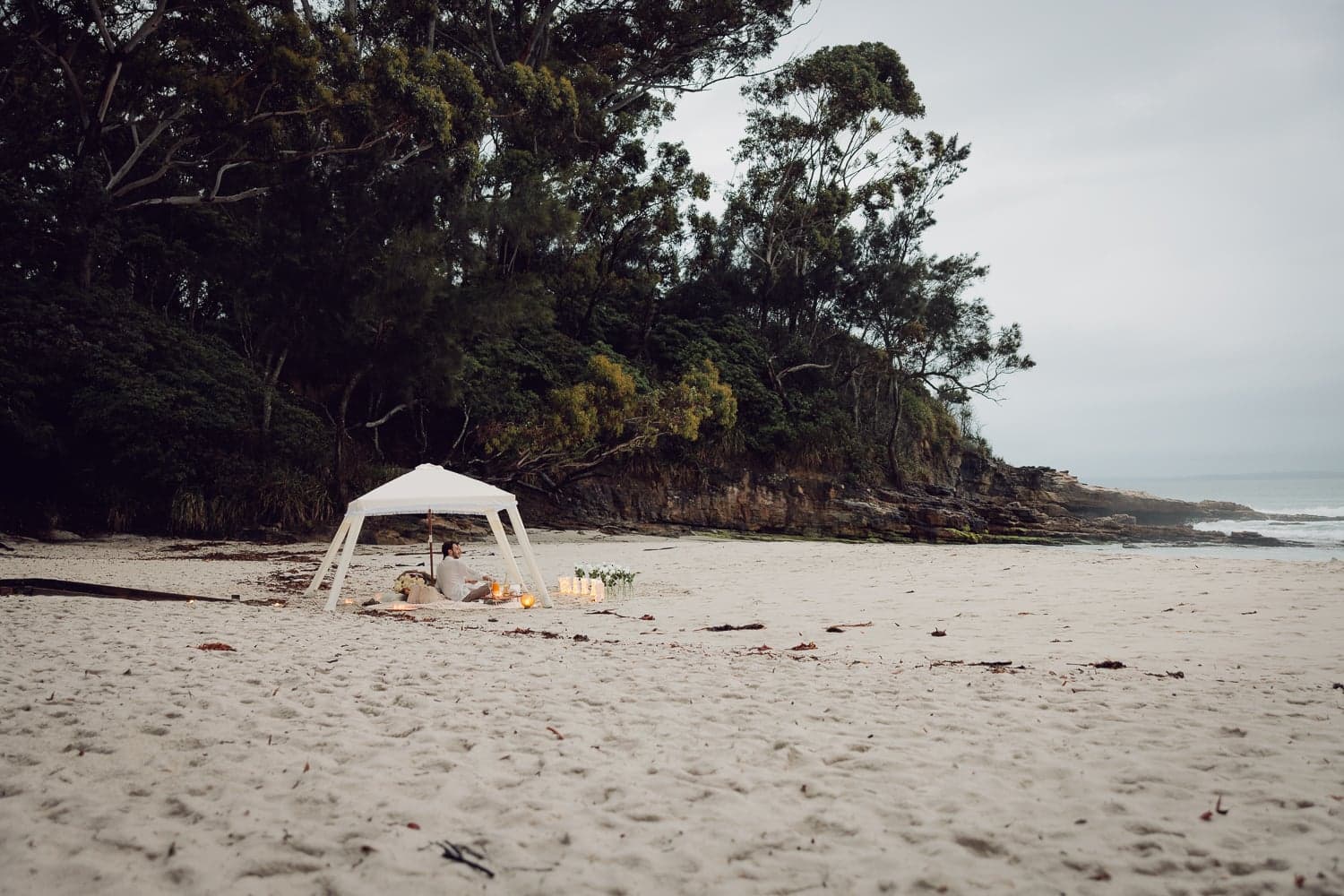 Wide shot of a candlelit beach picnic setup for a surprise proposal at Jervis Bay NSW, proposal photography by Martincito.